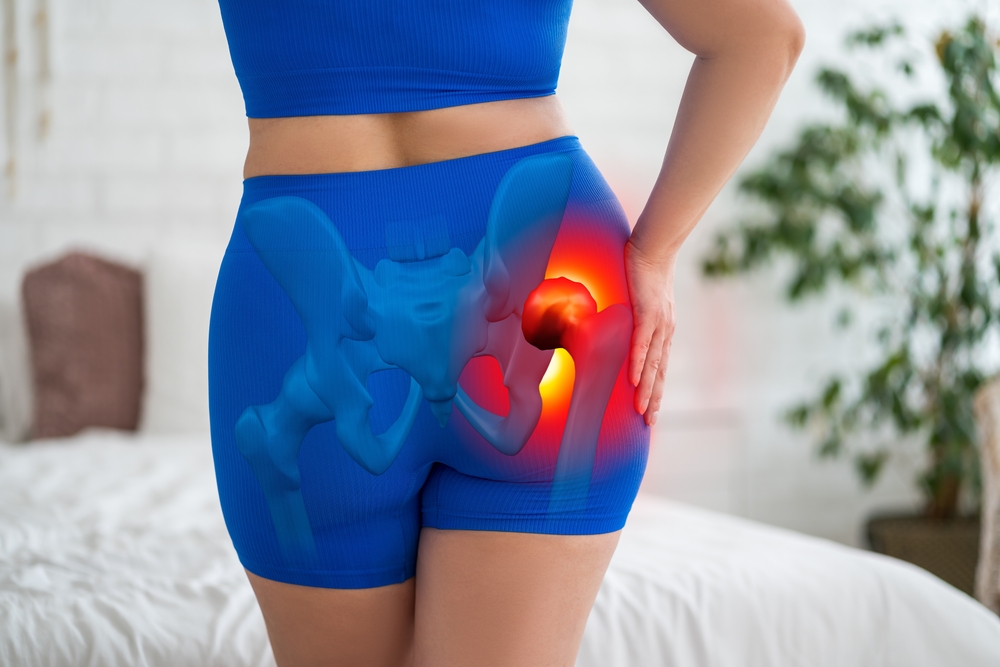 Woman at home holding her hip in discomfort, illustrating symptoms of hip dysplasia, joint inflammation, or pelvic osteoarthritis, highlighting chronic pain and mobility-related health issues.