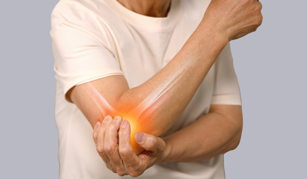 Close-up of a person’s arm showing signs of elbow pain, illustrating common conditions like tennis elbow and golfer’s elbow caused by repetitive strain or overuse.