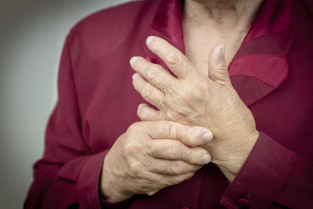 Woman holding her hand in pain, showing symptoms of hand arthritis and joint discomfort.