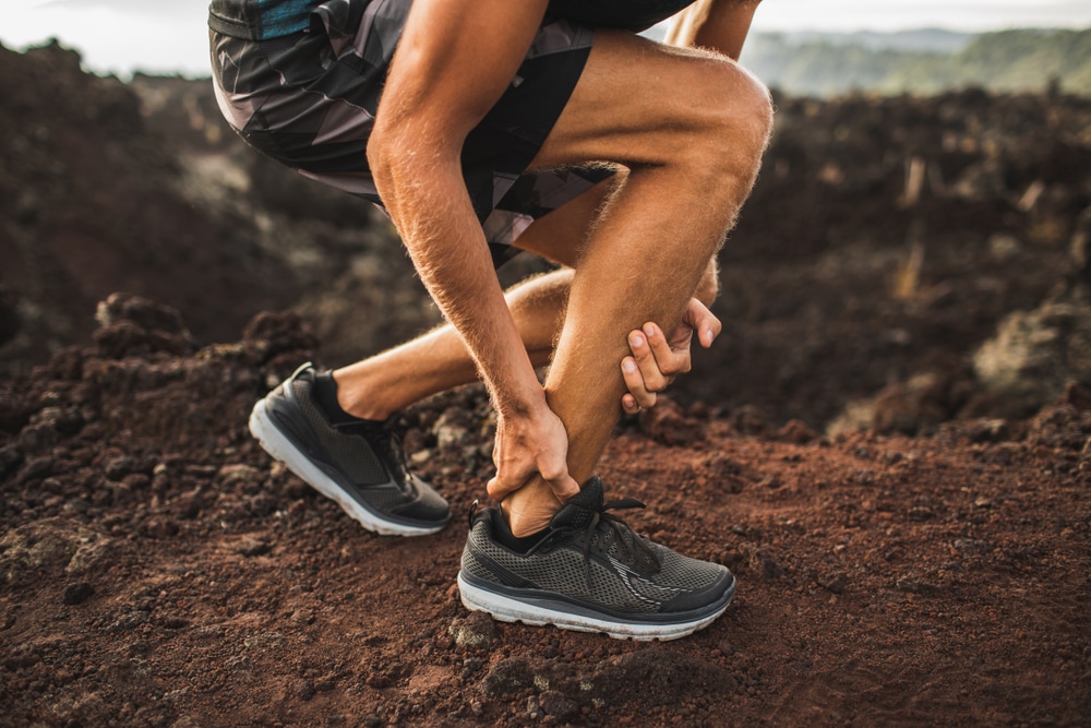 A cropped shot of a man with achilles tendonitis holding his ankle