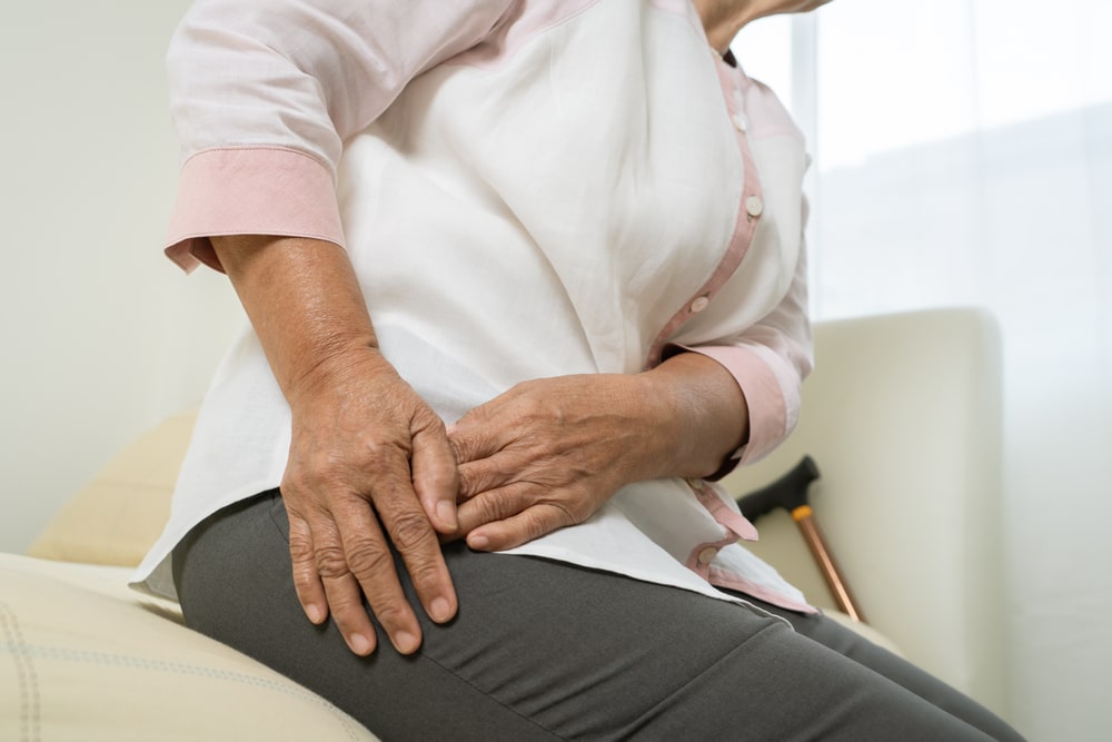 Senior woman holding her hip considering hip replacement in Union County