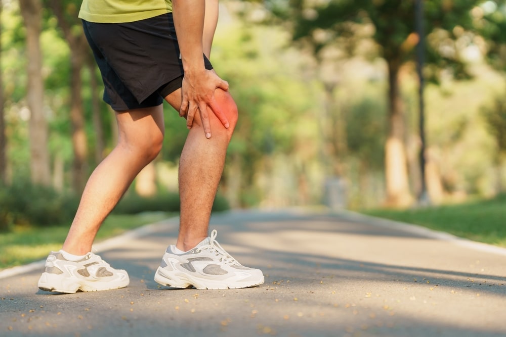 Man with a meniscus tear holding his knee while walking