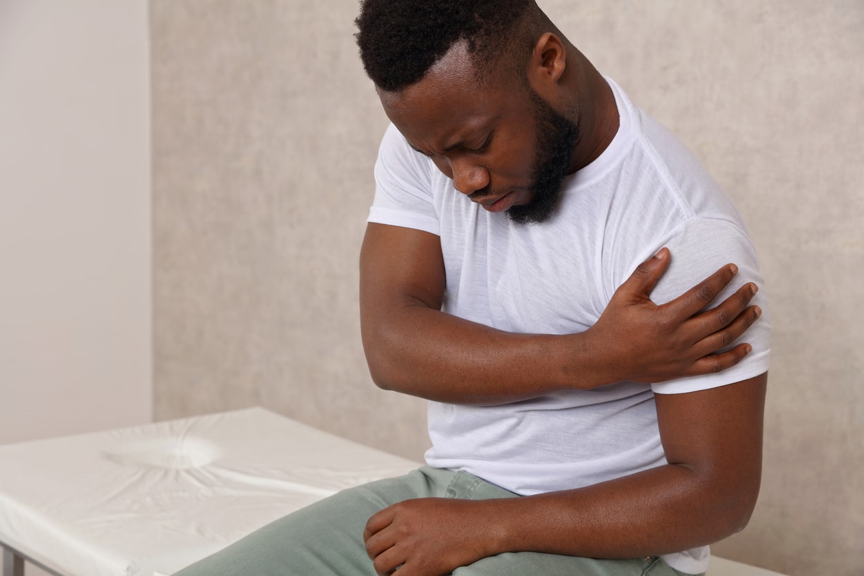 Man with a rotator cuff tear holding his shoulder