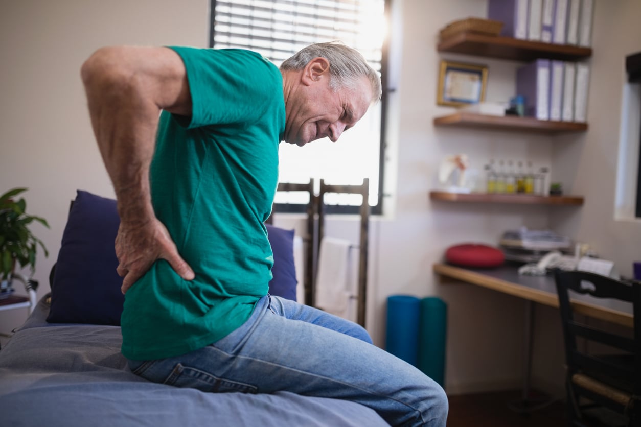 Man with back pain holding his lower back
